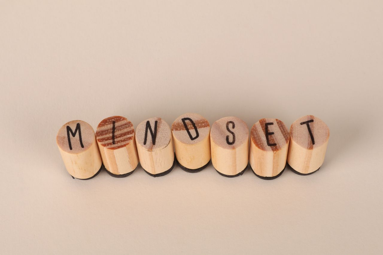 who-we-are Wooden letter stamps spelling Mindset on a simple beige background, conveying focus and positive thinking.